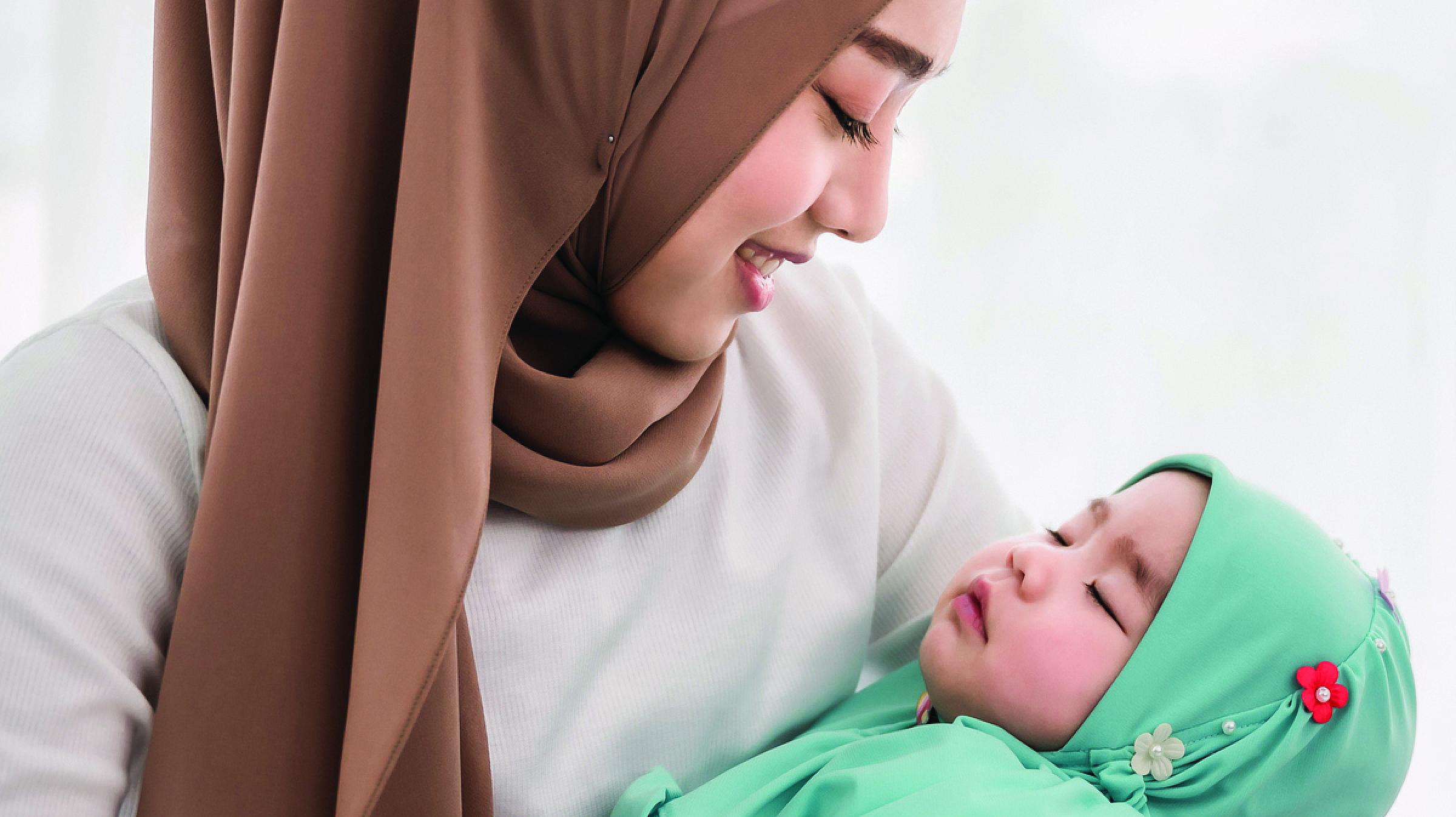Woman wearing hijab holding a baby